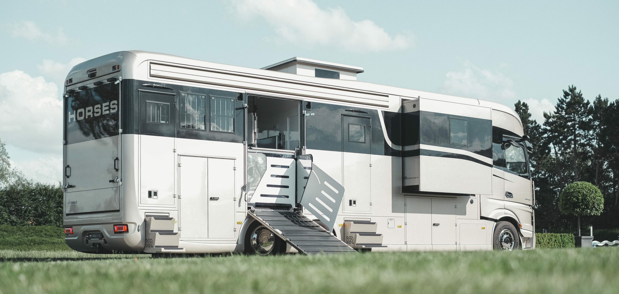 Een foto van een Krismar paardenvrachtwagen in een gouden kleur met een optische zwarte lijn.