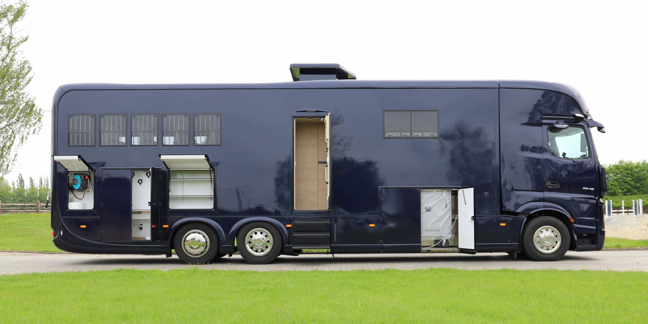 een foto van de zijkant van een Krismar paardenvrachtwagen in een donker blauwe kleur met alle deuren open