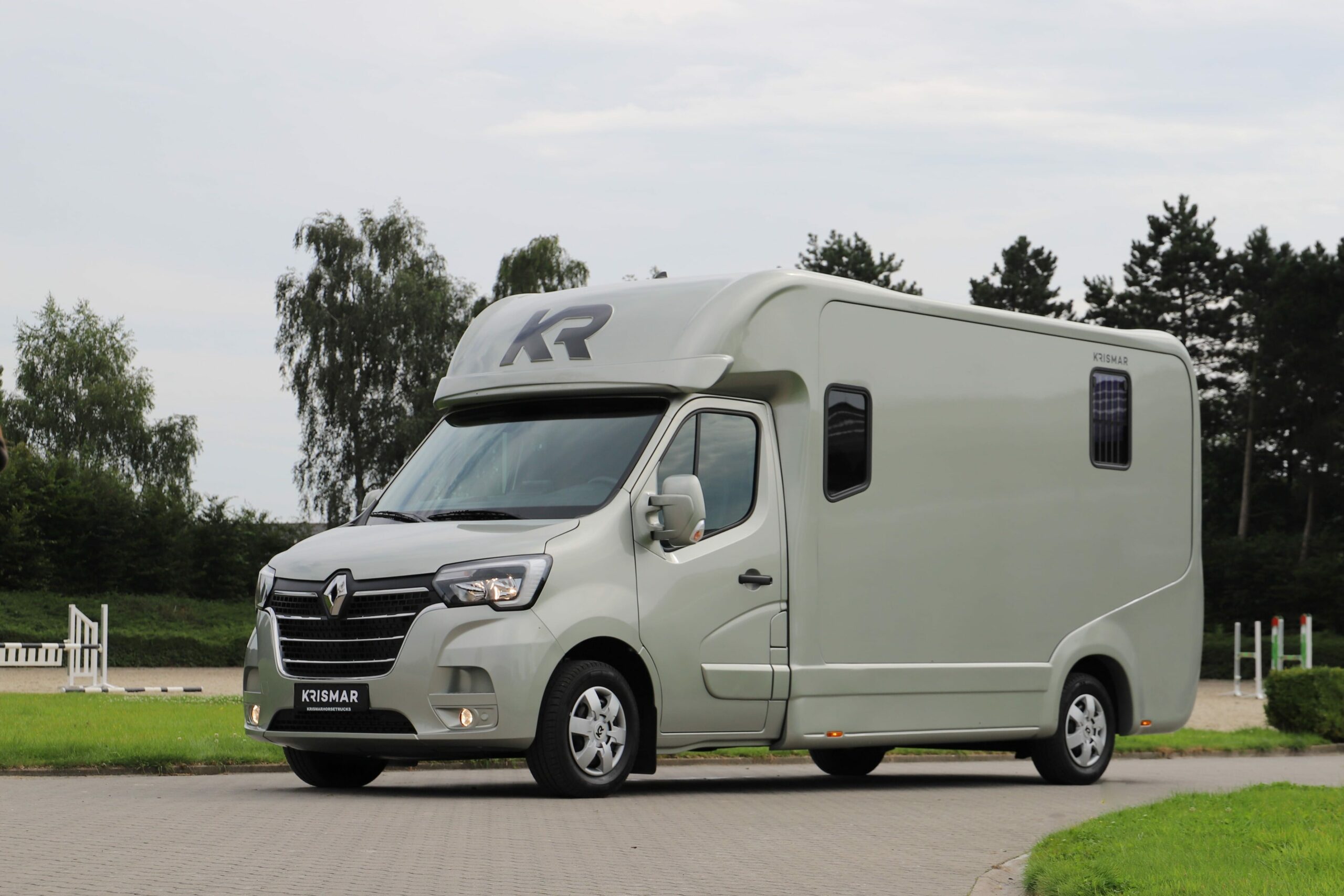 Een goudkleurige Krismar paardenvrachtwagen voor 2 paarden van het merk Renault.