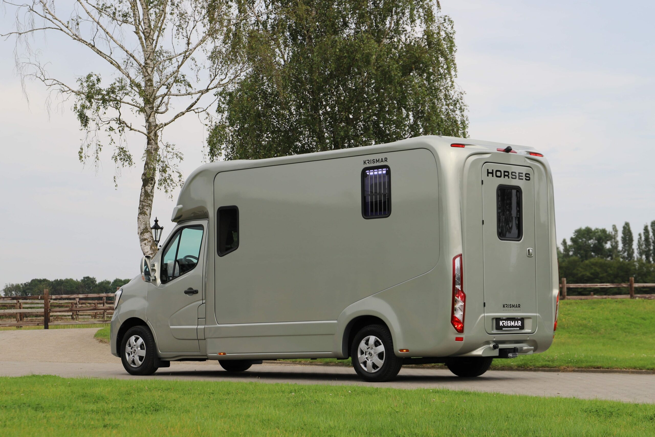 Een goudkleurige Krismar paardenvrachtwagen voor 2 paarden van het merk Renault.