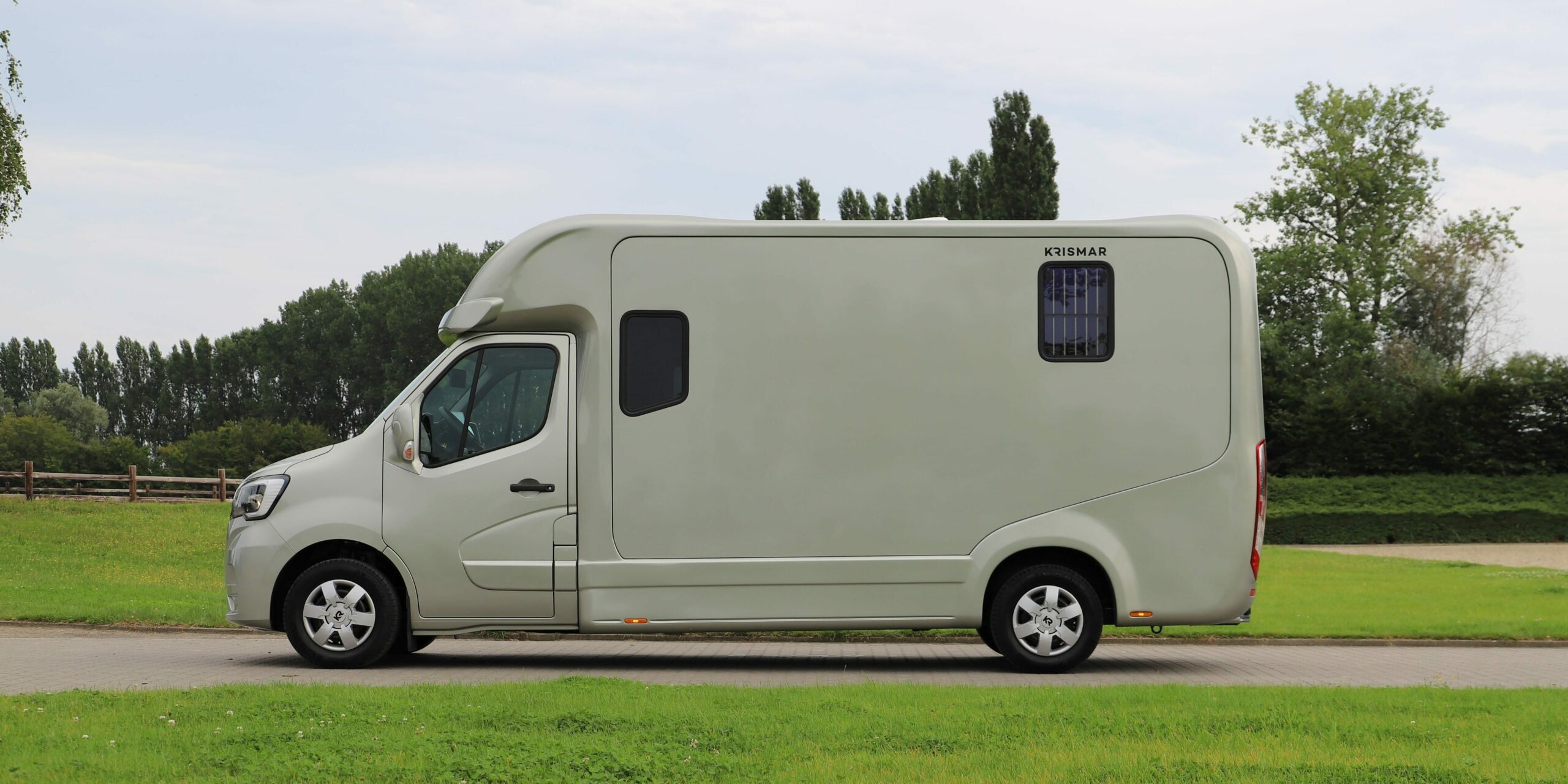 Een goudkleurige Krismar paardenvrachtwagen voor 2 paarden van het merk Renault.