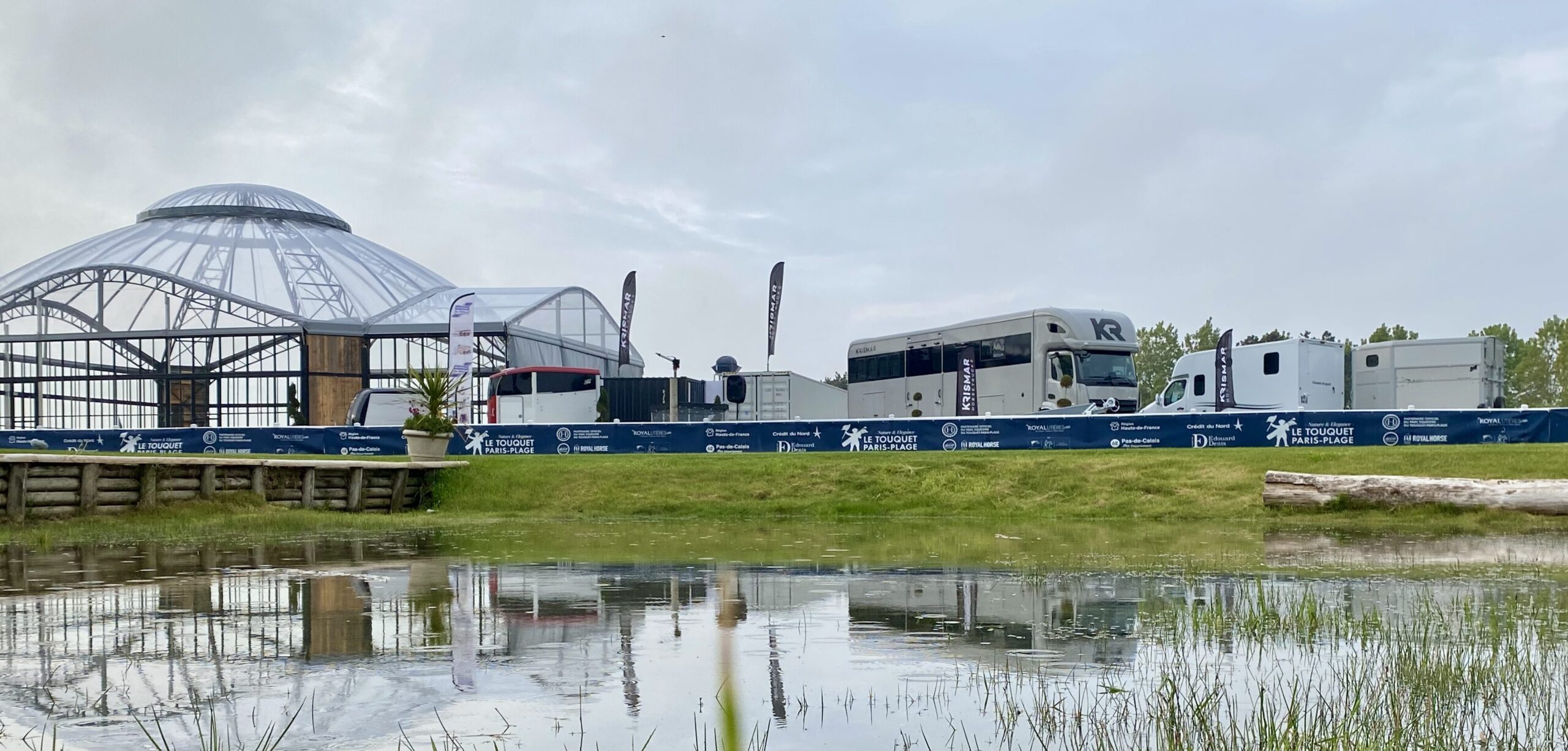 Een foto van de Krismar stand in Le Toquet genomen met een vijver tussen waardoor alles reflecteert in het water.