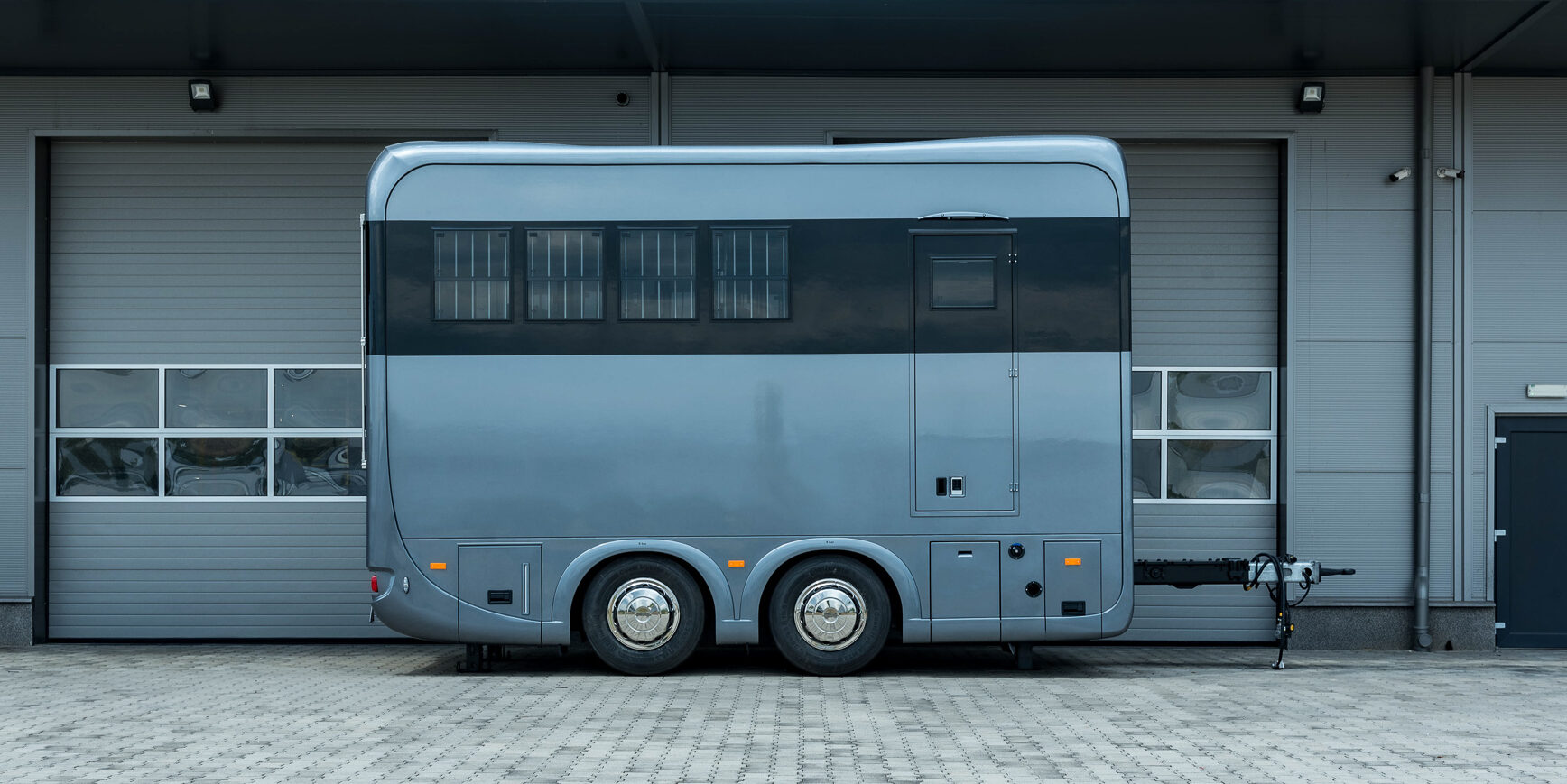 Zijaanzicht van een grijze 18 ton Krismar trailer met een zwarte optische lijn.