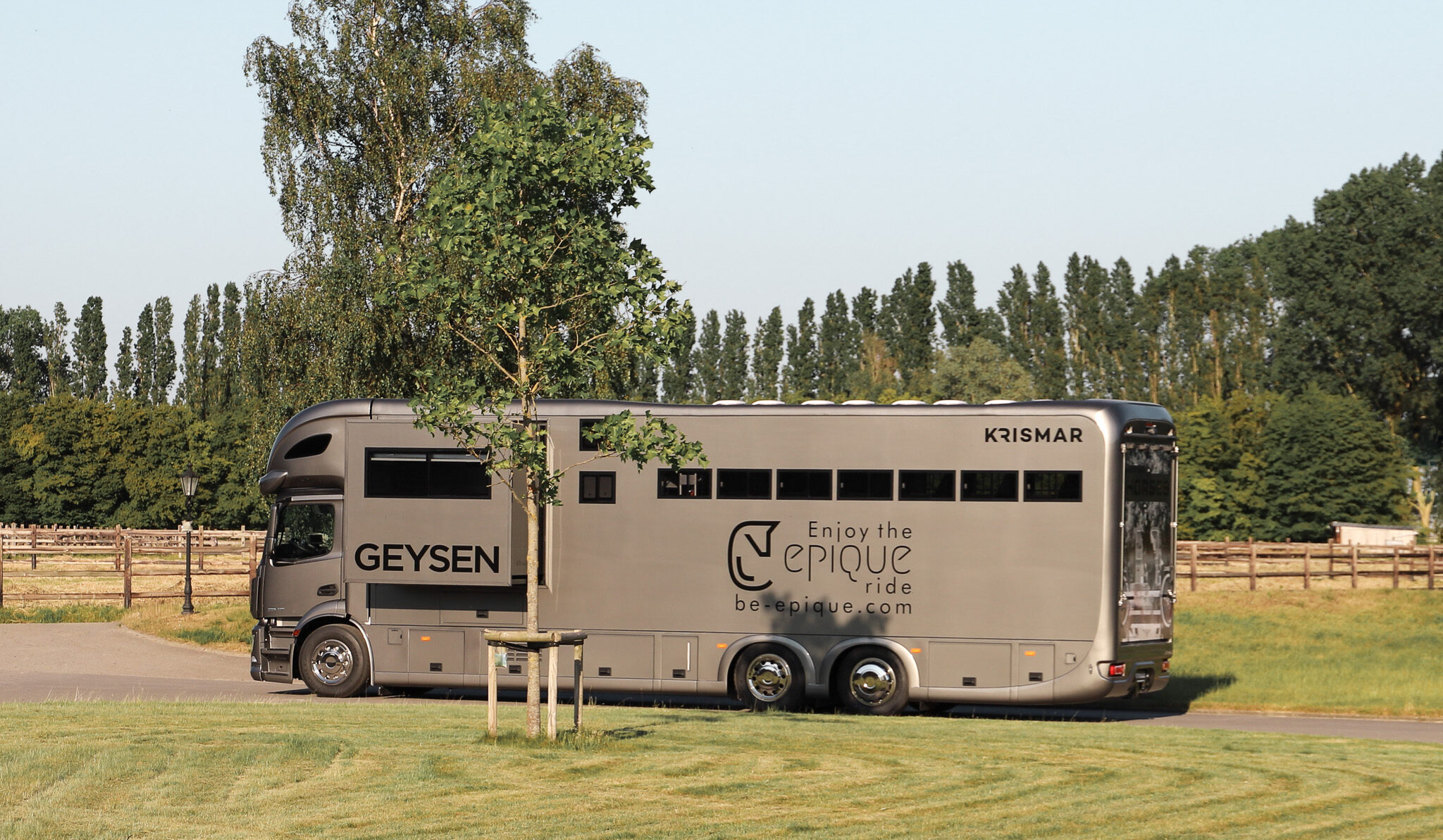 The side of a grey Krismar horse truck with logo from the customer on the pop-out.