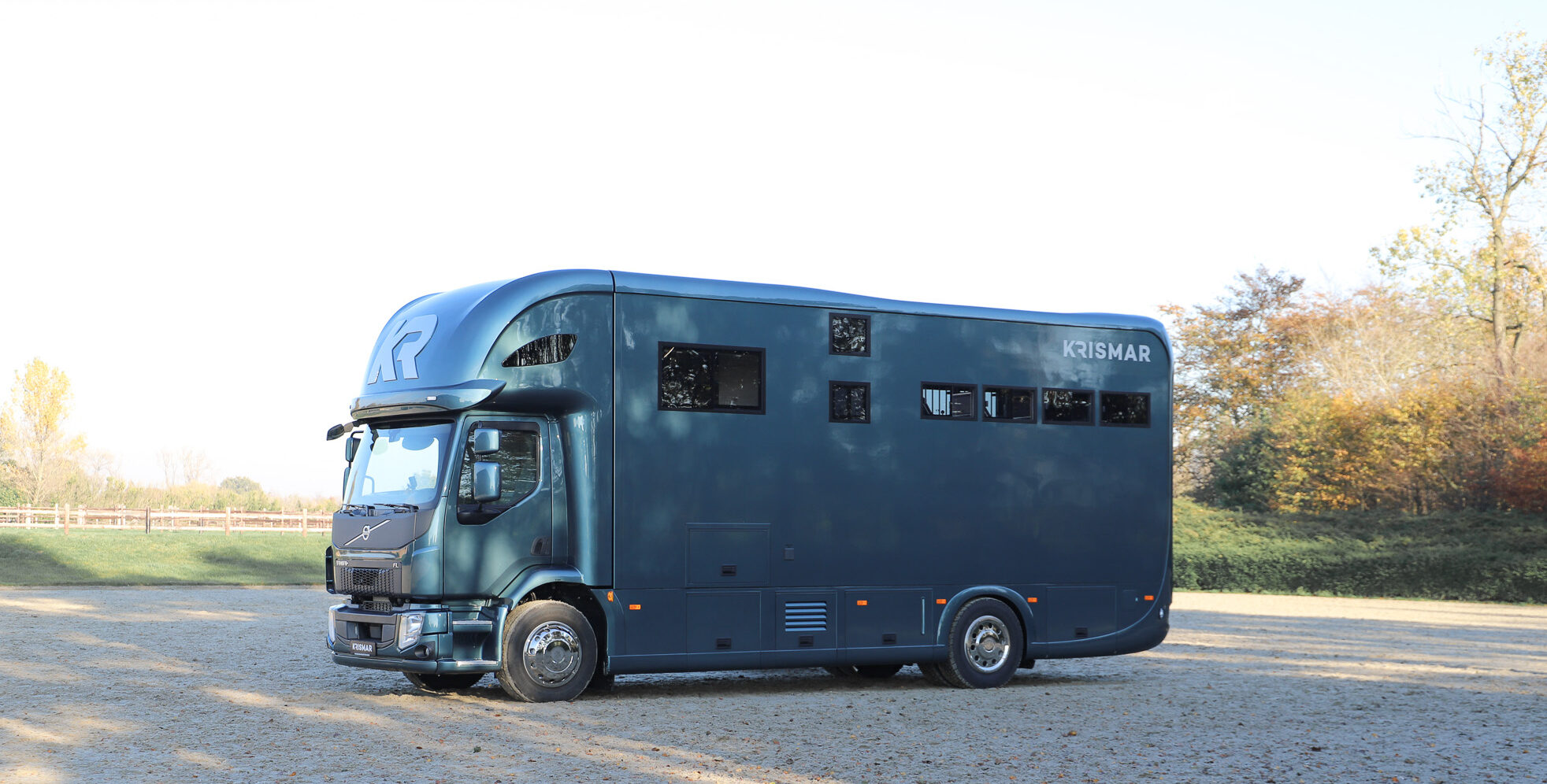 Zijkant van een Krismar paardenvrachtwagen in een mooie petrol groene kleur.