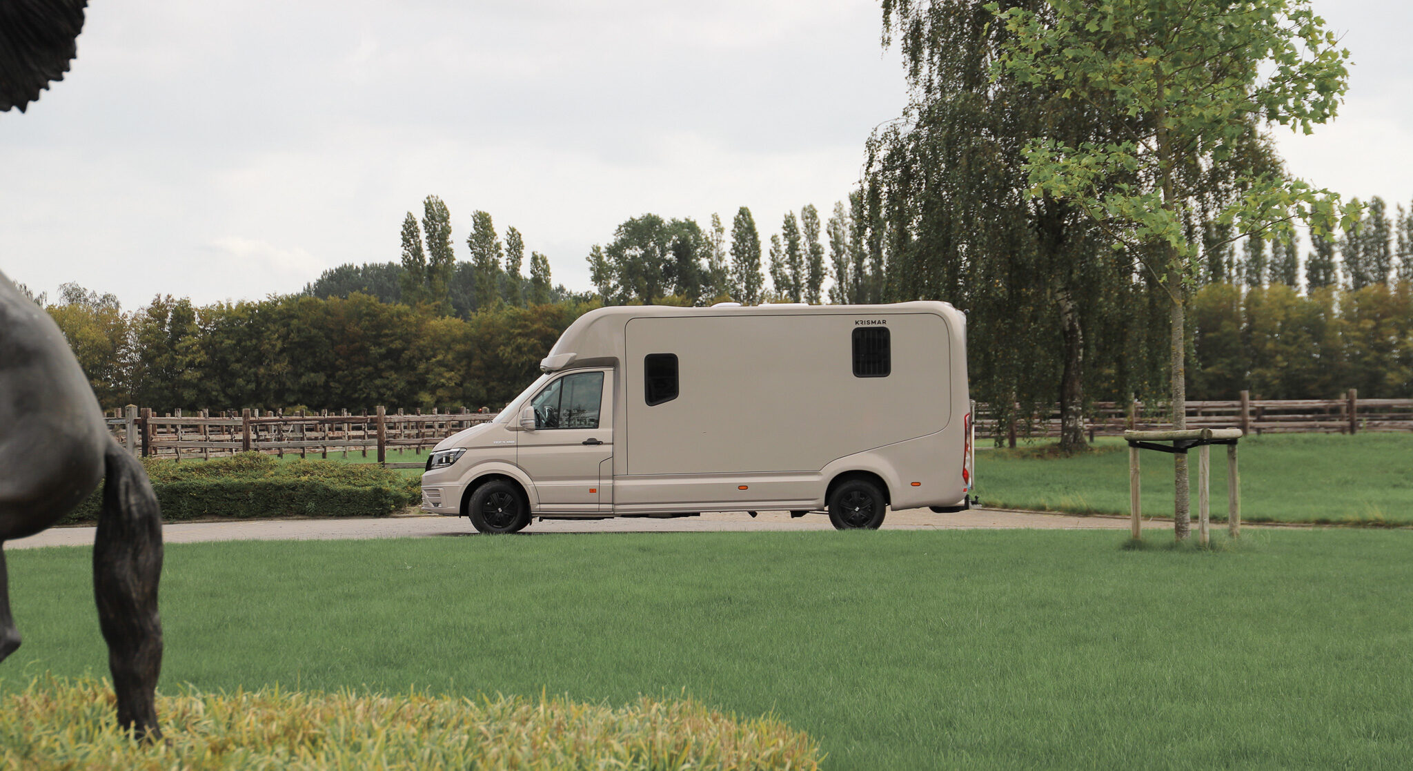 Een grijs/gouden Krismar 2-paards wagen met zwarte wielschijven.